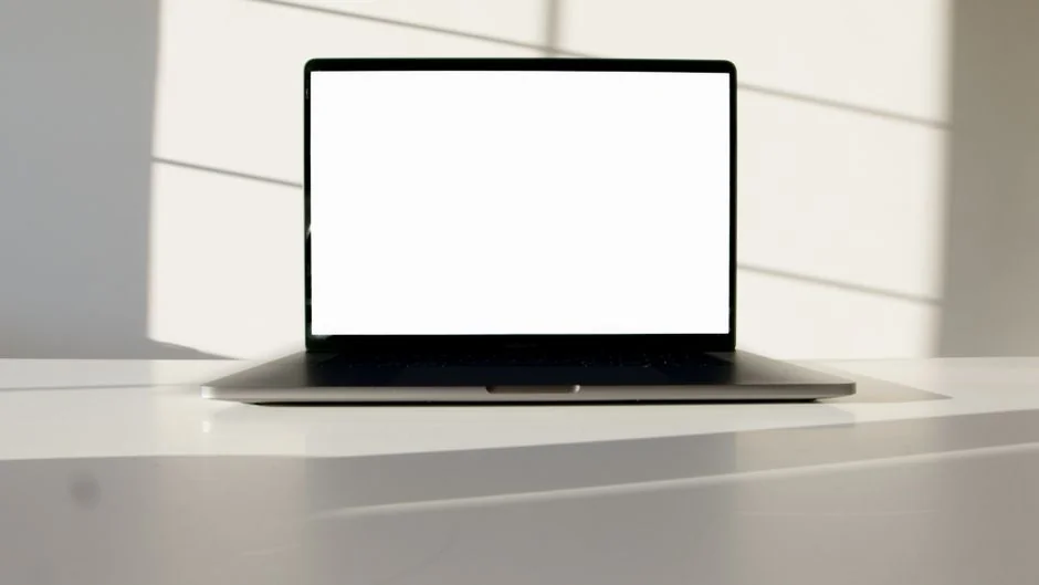 Vue rapprochée de mains tapant sur un ordinateur portable, à côté d’une tasse de café, sur un bureau en bois.